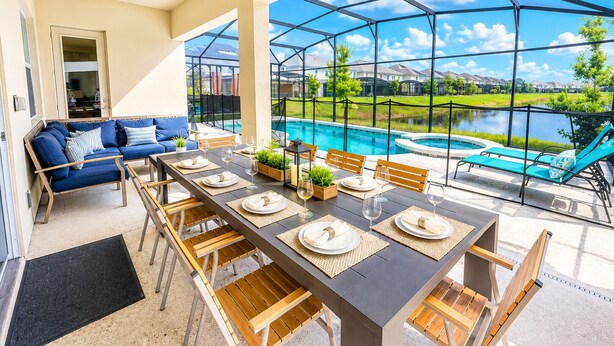 Un coin repas avec vue sur la piscine, un canapé et une table dressée pour quatre personnes.