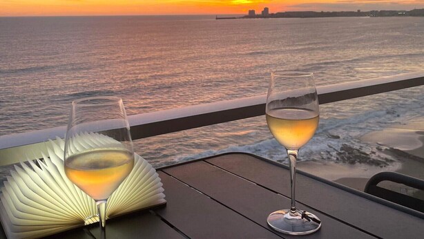A table with two glasses of white wine and a plate of sushi, overlooking a sunset over the ocean. - La P'Tite Case - facing the sea (Les Sables-d´Olonne)