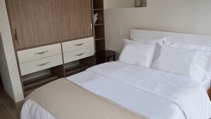 Quarto com cama, guarda-roupa e uma pequena mesa.