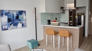 Uma cozinha moderna com ilha central, banquetas de bar e uma grande pintura abstrata na parede.