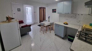 Une cuisine moderne avec un coin repas, des meubles blancs et un sol carrelé.