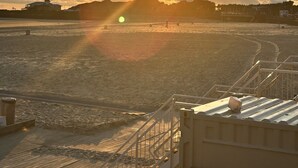 A beach with a sunset, a staircase, and a building in the background. - Chalet in the family paradise "Olmenveld", Zeeland (Serooskerke)