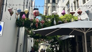 A narrow street with historic buildings, a prominent clock tower, and hanging lanterns. - Chalet in the family paradise "Olmenveld", Zeeland (Serooskerke)