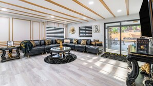 A modern living room with a black leather sofa, a glass coffee table, and a book titled "In His Own Fashion" by Ralph Lauren. - Blackrock Lux ~ High-End Designer Oasis ~ 7min from Airport ~ EV Charger (Fort Lauderdale)
