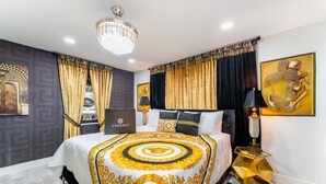 A modern bedroom with a large bed, a chandelier, and a gold-framed artwork on the wall. - Blackrock Lux ~ High-End Designer Oasis ~ 7min from Airport ~ EV Charger (Fort Lauderdale)