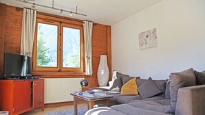 Kodikas olohuone, jossa on sohva, televisio ja shakkilauta puupöydällä.