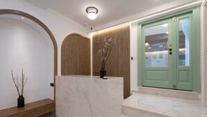 A reception area with a marble counter, wooden panel wall, and a green door. - SARTORI CONCEPT HOTEL (Heraklion)