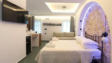 Ein modernes Hotelzimmer mit Bett, Schreibtisch, Flachbildfernseher und einer Wand mit Steinverkleidung.