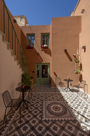 A courtyard with a checkered floor, a staircase, and a door. - SARTORI CONCEPT HOTEL (Heraklion)