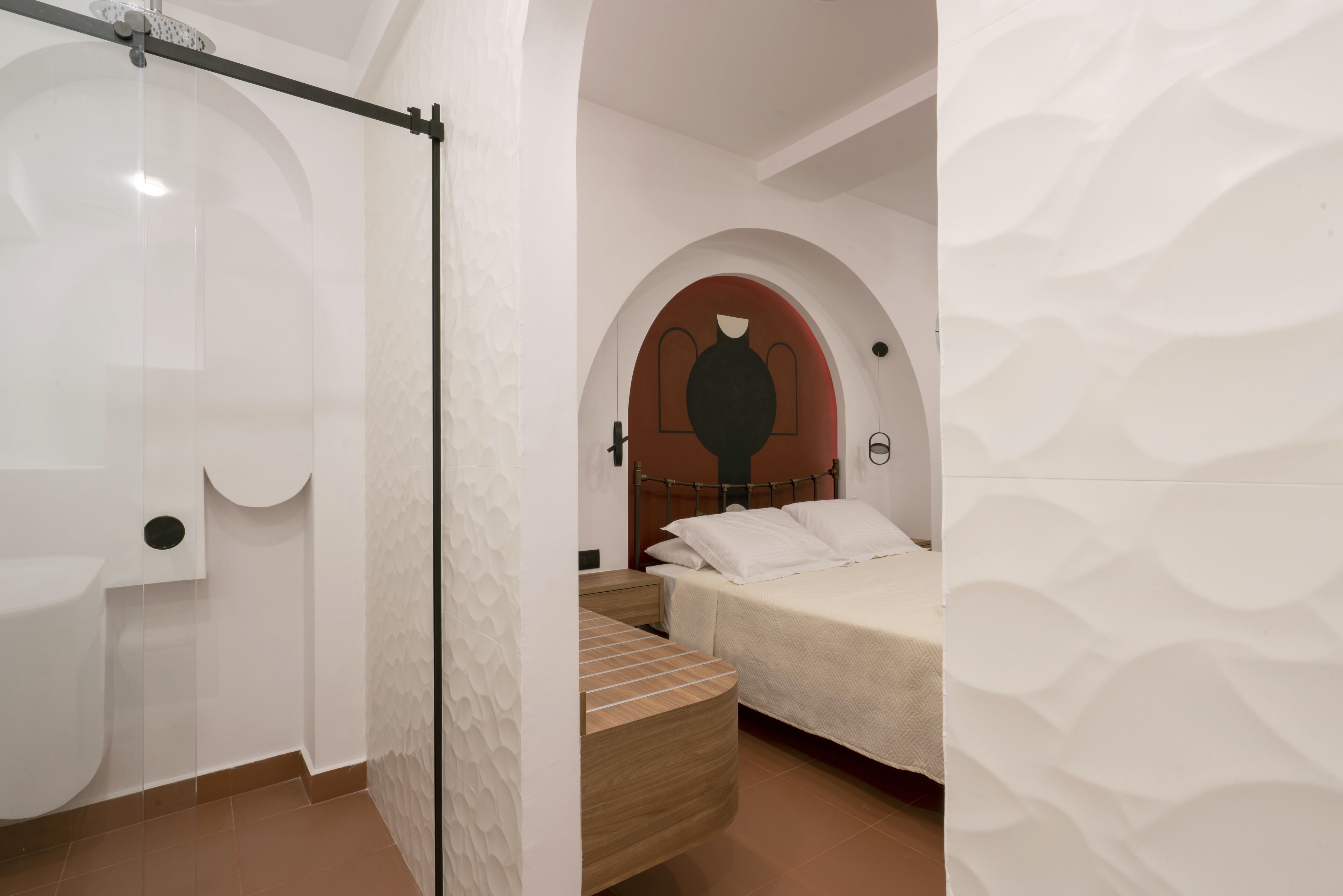 Une chambre à coucher comprenant un lit, une table de chevet, un banc en bois et un espace douche.