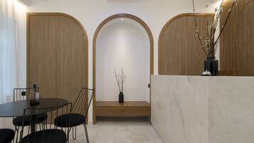 A reception area with a marble reception desk, a bench, and a small table with chairs.