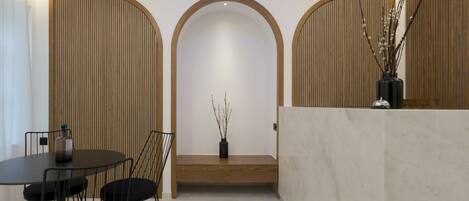 A reception area with a marble reception desk, a bench, and a small table with chairs.