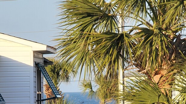 A white building with a balcony and a street lamp in front. - Carolina Rose - Steps from the Beach in Oceanside Village (Surfside Beach)