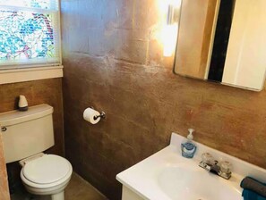 A bathroom with a toilet, a sink, and a mirror.