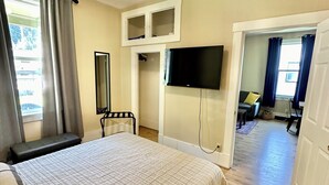 A bedroom with a bed, a TV, a wardrobe, and a mirror.