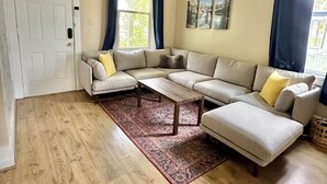 A living room with a beige sofa, a wooden coffee table, and a patterned rug.