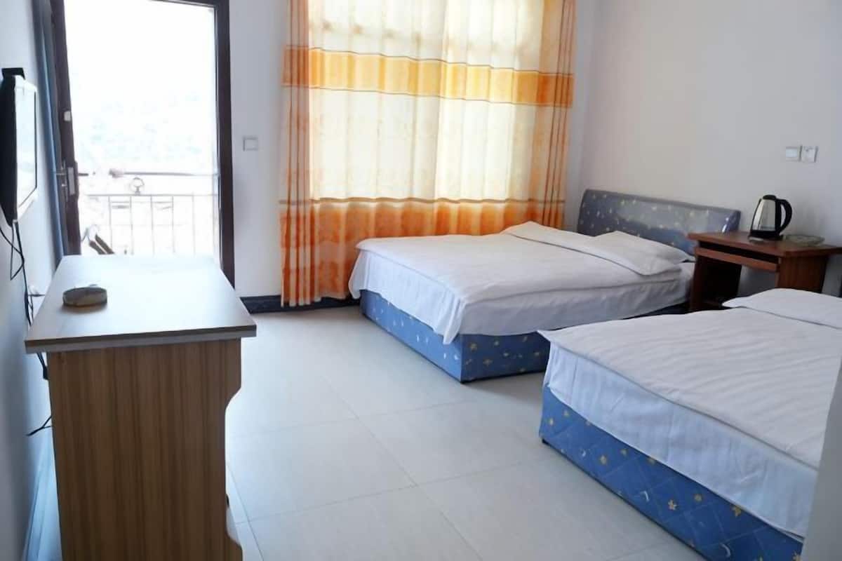 A hotel room with two beds, a desk, a chair, a television, and a window with curtains.