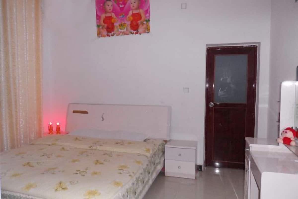 A bedroom with a bed, a nightstand, a dresser, a door, and a wall decoration.