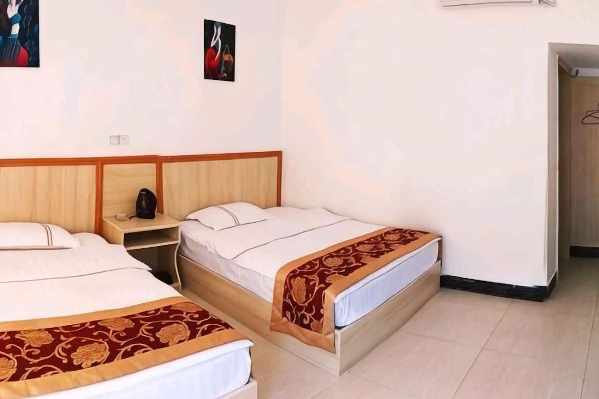 Two single beds with wooden headboards, a bedside table with a lamp, and a small shelf.