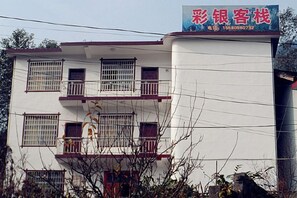 A multi-story building with a signboard, balconies, and a visible window pattern. - Caiyin Inn (Zhangjiajie)