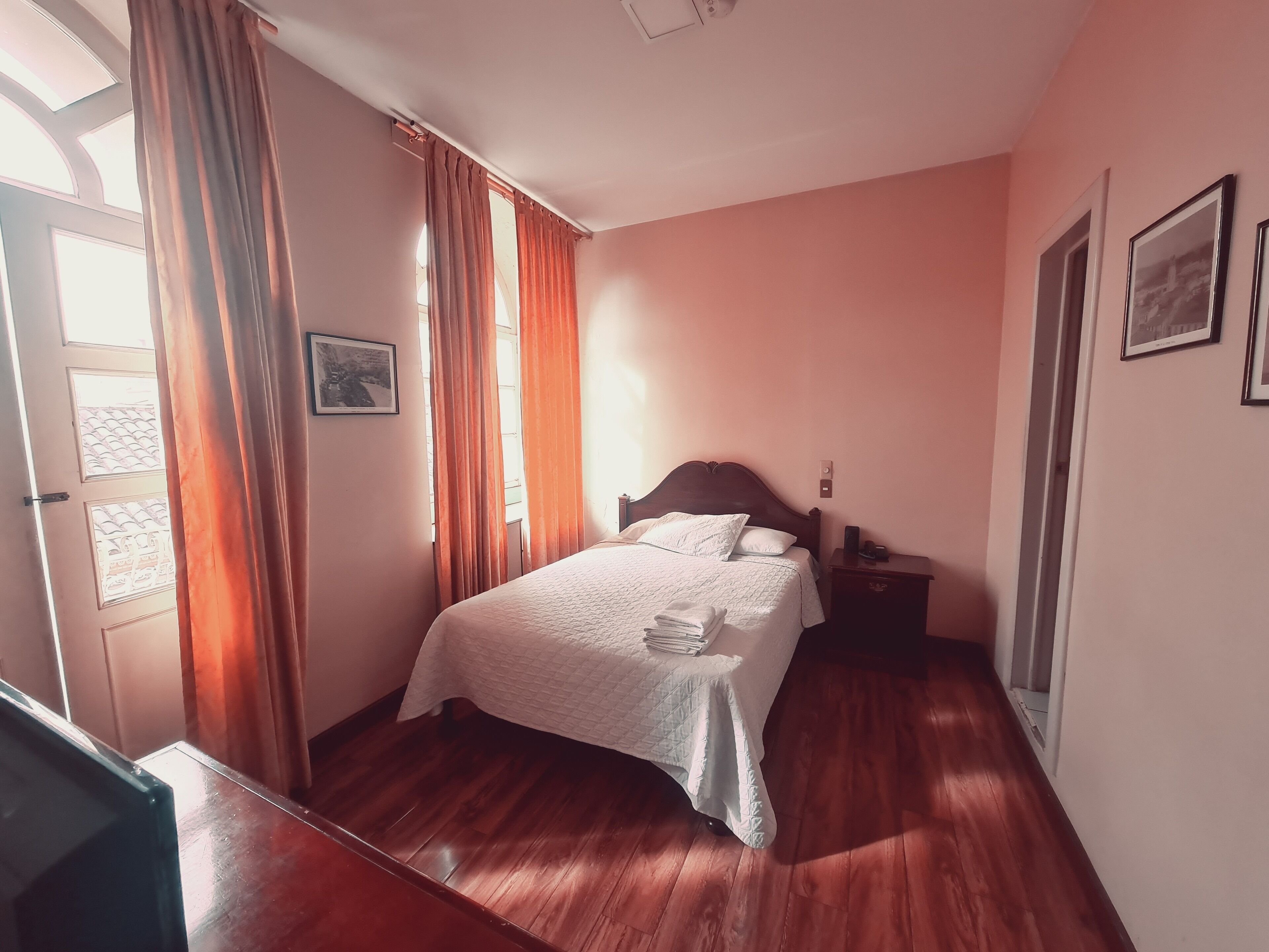 Un dormitorio con cama, mesita de noche, escritorio y una puerta.