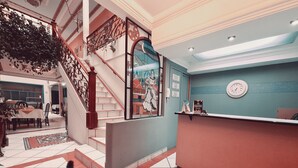 A hotel lobby with a staircase, a reception desk, and a dining area. - Hotel Chat Noir Cuenca (Cuenca)