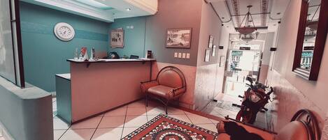 A reception area with a desk, a chair, a clock, and a patterned rug.