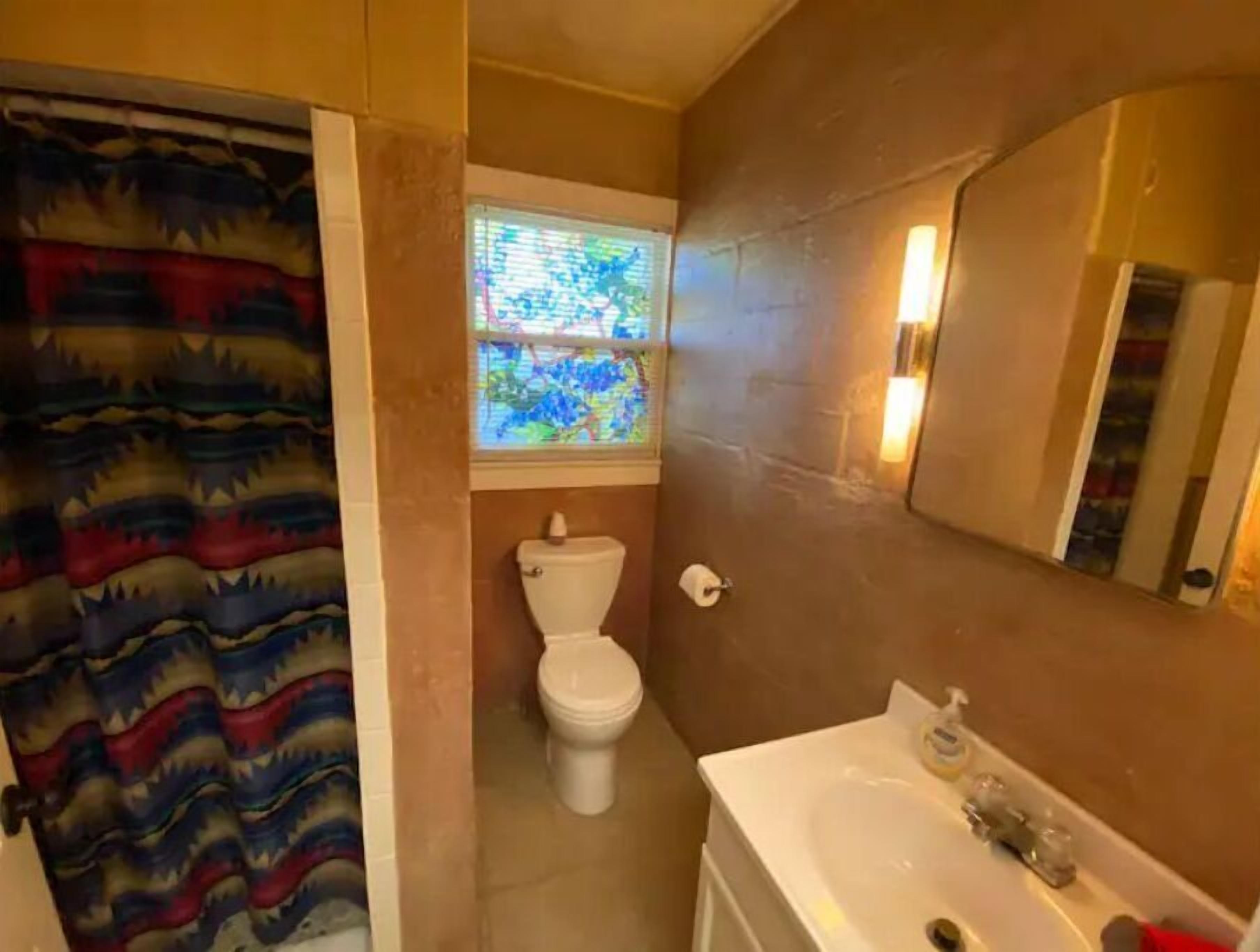 A bathroom with a toilet, a sink, and a window with a stained glass design.