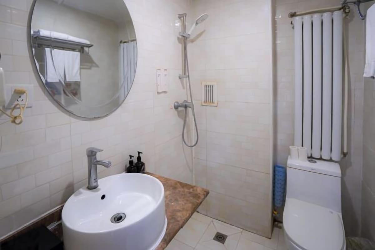 A bathroom with a sink, mirror, shower, and toilet.