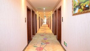 A hotel hallway with wooden doors, a floral carpet, and a framed painting on the wall. - Junyi · Leishen Jingjie E-Sports Hotel (Beijing Yanqing Global Xinyi Department Store) (Beijing)