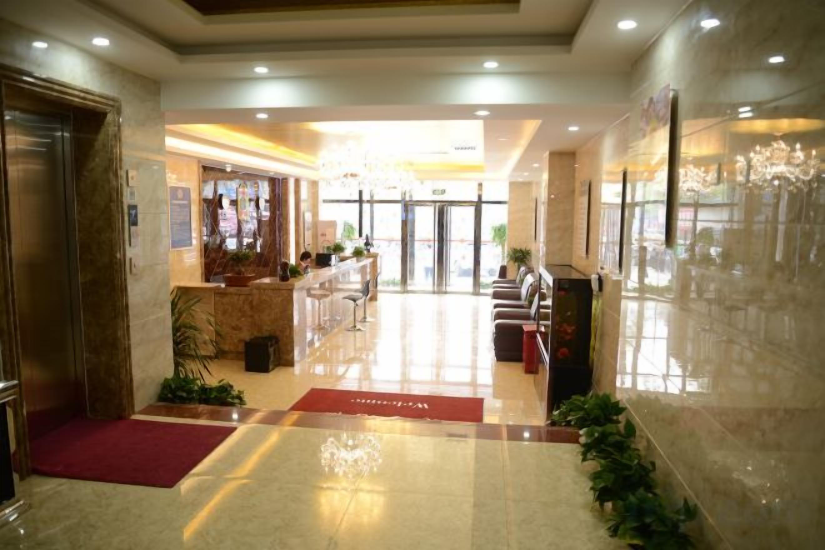 Un hall de hotel con mostrador de recepción, zona de estar y un candelabro.