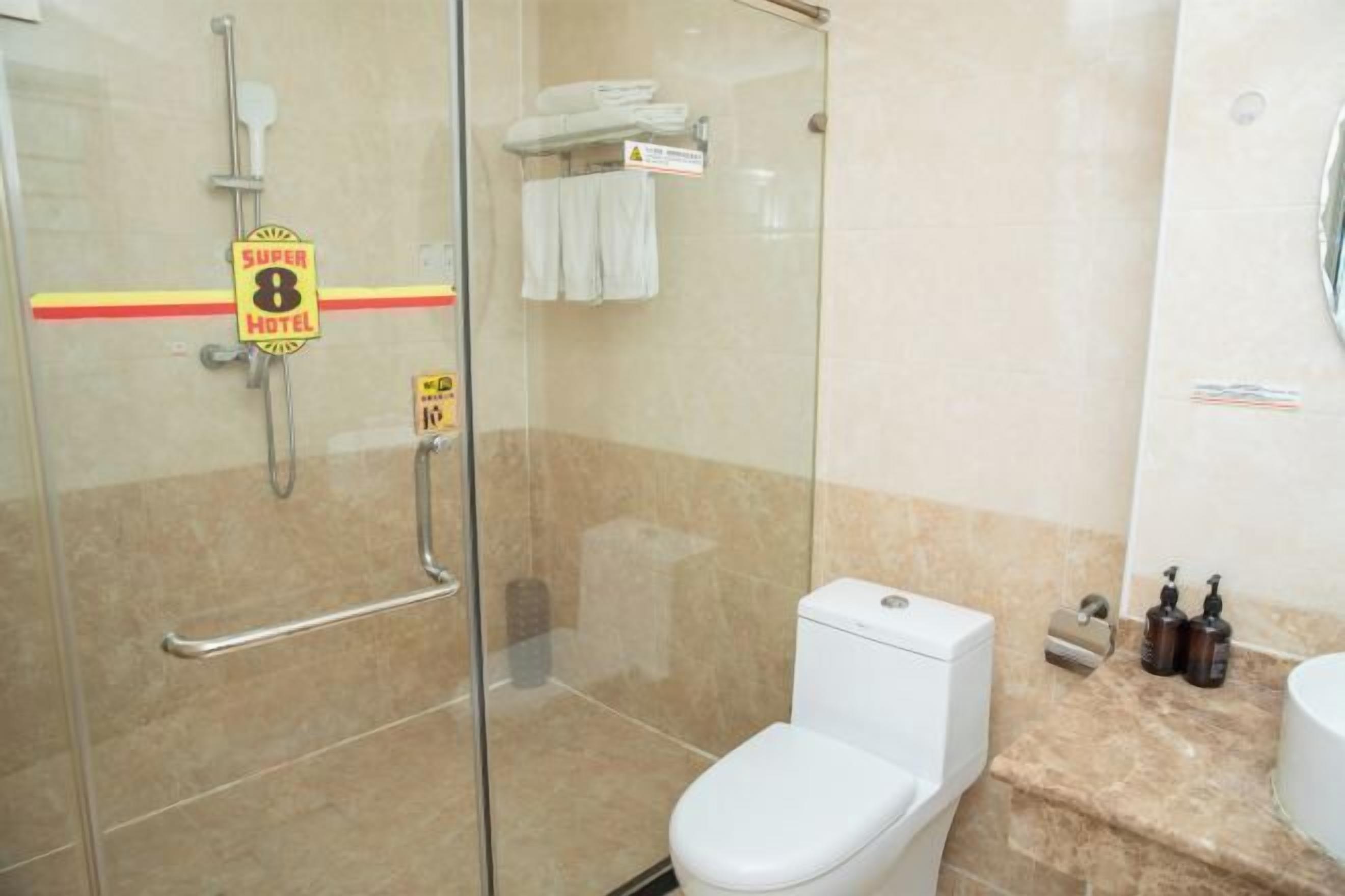 Casa de banho de hotel com cabine de duche em vidro, sanita e zona de lavatório.