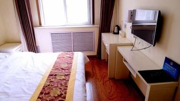 A hotel room with a bed, a desk, a television, and a window with curtains.