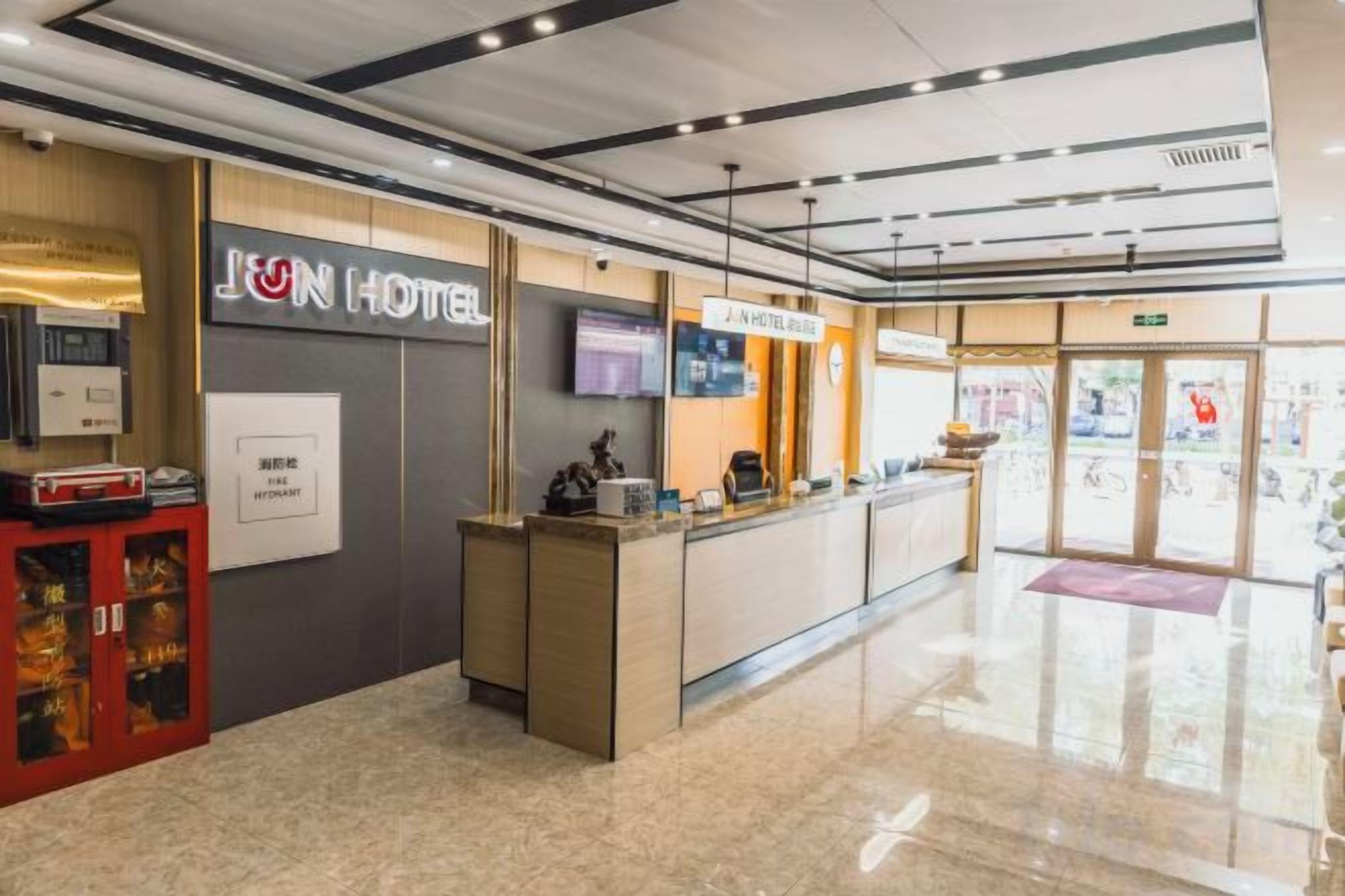 Een hotel receptie met een receptiebalie, een televisie en een scherm dat informatie toont.