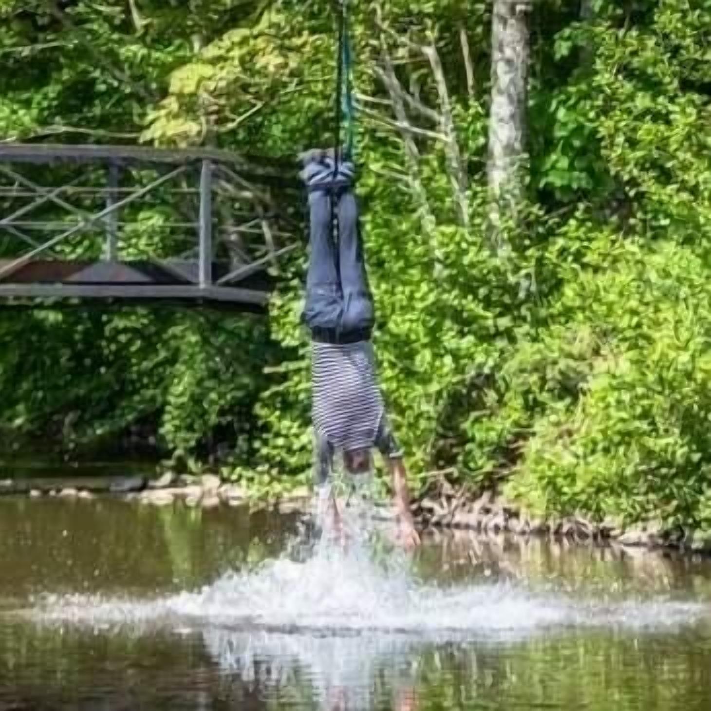 Henkilö tekee pääseisontaa vesistössä, taustalla näkyy silta.