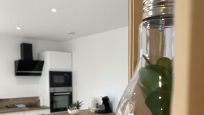 Een moderne keuken met een eethoek, met een glazen fles met een plant en kiezelstenen.