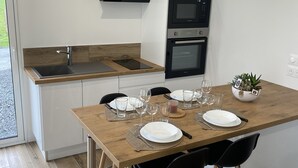 Een moderne keuken met een houten eettafel gedekt voor vier personen, een inbouwoven en een zwarte afzuigkap.