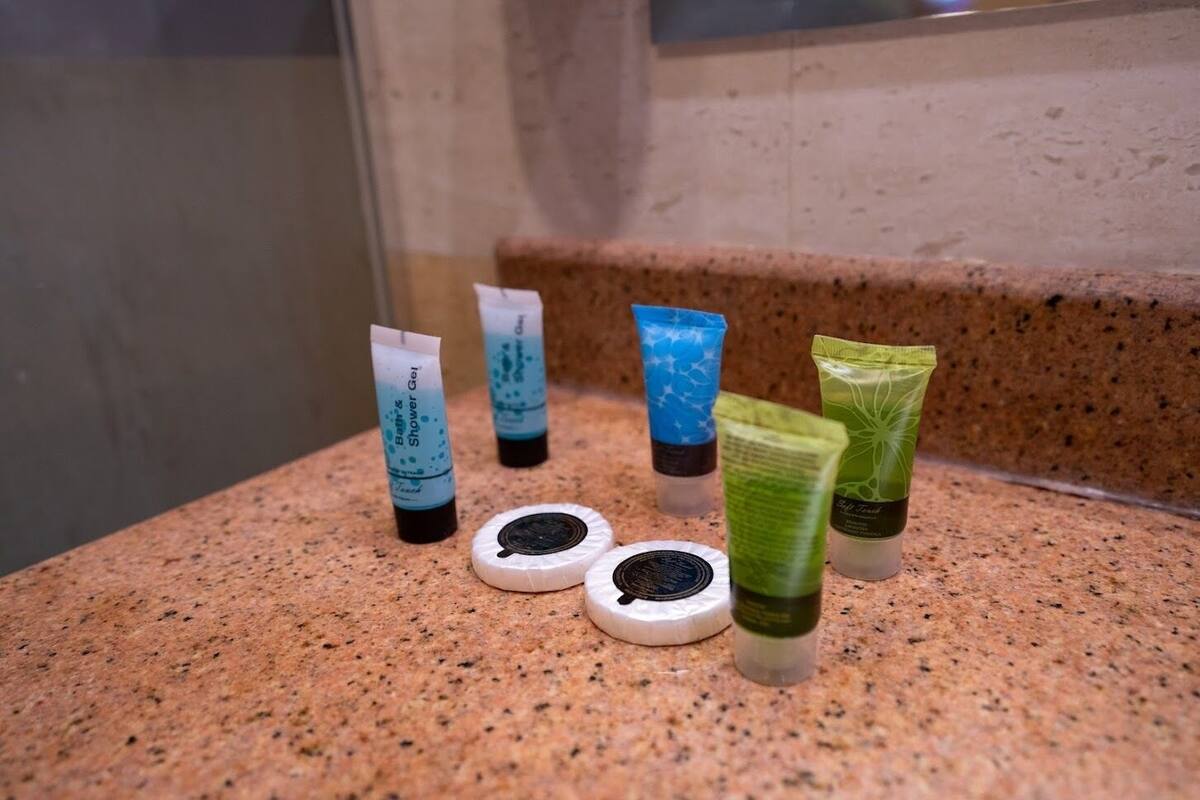 A countertop with various toiletries including a tube of shower gel, a tube of lotion, and a tube of shampoo.