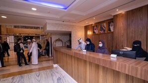 Et hotellets receptionområde med en træreception, en marmorgulv og indrammede portrætter på væggen.