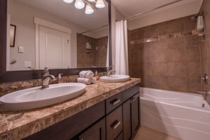Ein Badezimmer mit zwei Waschbecken, einer Badewanne, einer Dusche und einem großen Spiegel.
