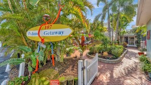 A sign for '107 Island Getaway' with a tropical garden setting. - Tropical Charm Steps 2 Beach/Walk 2 Bridge St (Bradenton Beach)
