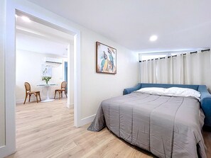 A bedroom with a bed, a chair, a table, and a painting on the wall. - Vintage Tropical Charm Steps 2 Beach/Walk 2 Bridge (Bradenton Beach)