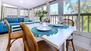 A dining area with a white table, blue placemats, and wicker chairs. - Tropical Charm Steps 2 Beach/Walk 2 Bridge St (Bradenton Beach)