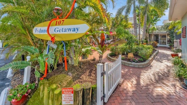 A sign for 'Island Getaway' with a number '107' and a 'RESERVED PARKING' sign nearby.