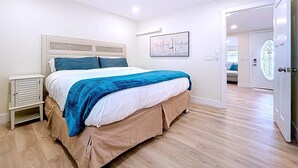 A bedroom with a bed, a nightstand, a painting, and a door.