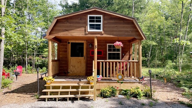 Une cabane en bois avec une véranda, une petite fenêtre et une porte.