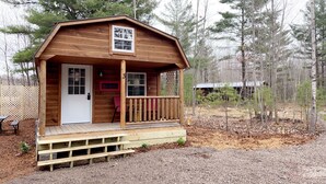Une petite cabane en bois avec une véranda, une porte et une fenêtre.
