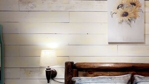 Une chambre à coucher avec une tête de lit en bois, une table de chevet, une lampe fixée au mur et un tableau représentant des tournesols.