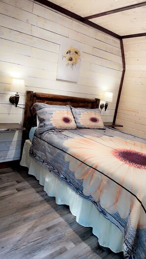 Une chambre à coucher avec une tête de lit en bois, une literie à motifs floraux et deux lampes de chevet.