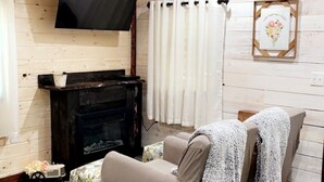 Un salon chaleureux avec une cheminée, un téléviseur et un canapé confortable.